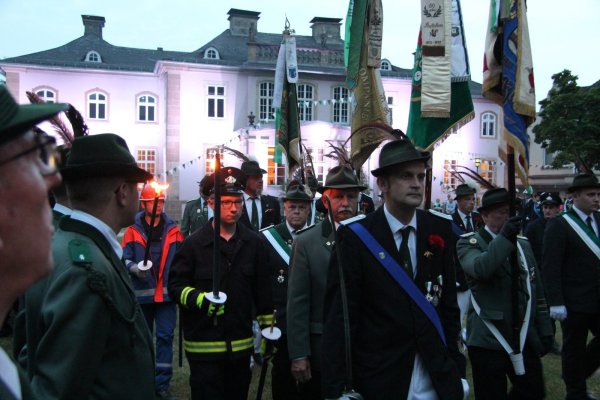 Feierlicher Einmarsch: Begleitet von Fackelträgern der Freiwilligen Feuerwehr geht der Ehrenzug der Fahnenträger an den Schützenkameraden vorbei. Das illuminierte Schloss bildet die stimmungsvolle Kulisse für den Zapfenstreich. - © Stefan Backe