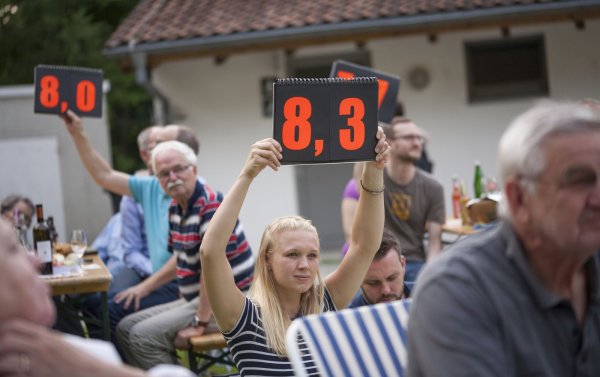Die Zuschauer entscheiden: Fünf Juroren aus dem Publikum vergeben beim Dichterwettstreit im Freilichtmuseum die Punkte, die sie auf Tafeln in die Höhe halten. - © Laurenz Tegethoff