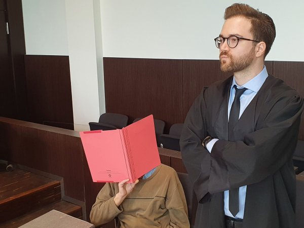 Der Angeklagte (l) sitzt neben seinem Verteidiger Maximilian Klefenz im Verhandlungssaal des Düsseldorfer Landgerichts und verdeckt sein Gesicht. - © Martin Höke/dpa