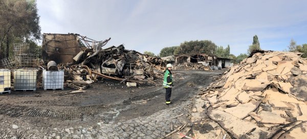 Berge von verbranntem Schutt: Feuerwehr-Pressesprecher Daniel Hobein steht auf dem Einsatzgelände an der Ladestraße. Das gesamte Material ist Fall für den Sondermüll. - © Thomas Reineke