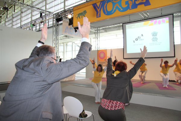 Yoga im Anzug: Lehrerin Gauri (im Hintergrund) animiert Besucher der Hannover Messe in der Halle zum Mitmachen. Geübt wird die "Business"-Variante der Entspannungstechnik. - © Reineke