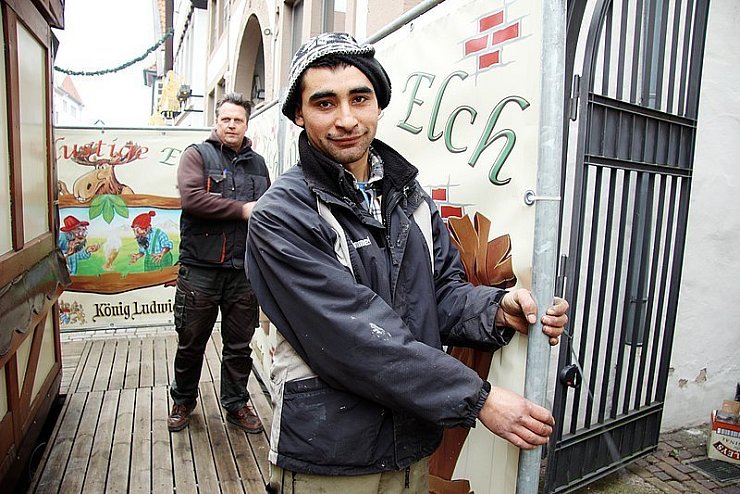 Falls die Orkanböen kommen, werden diese provisorischen Wände entfernt: Nicolaie Cârneala und sein Chef Antonio Noack beim Aufbau eines Glühwein-Standes in der Mittelstraße. - © Foto: Reineke