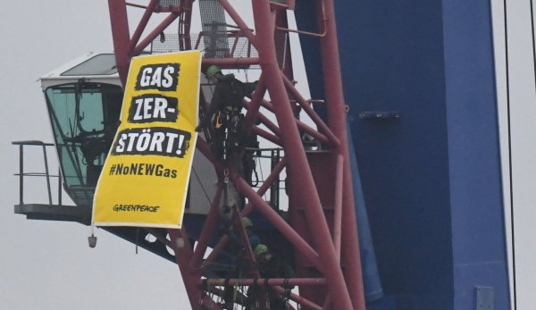 Greenpeace-Aktivisten protestieren auf einem Kran gegen den Start der Verlegung einer Gas-Pipeline im Hafen von Mukran im Norden der Insel Rügen. - © Stefan Sauer/dpa