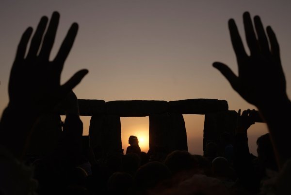 Menschen versammeln sich bei Sonnenaufgang am Tag der Sommersonnenwende um den Heel Stone in Stonehenge. - © Kin Cheung/AP