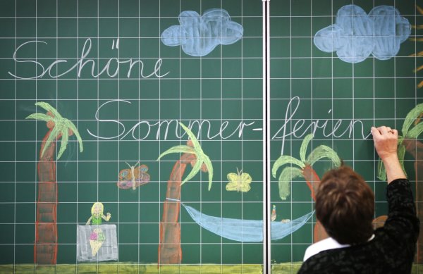 Eine Lehrerin schreibt «Schöne Sommer-ferien» an eine Tafel in einer Schule. - © picture alliance/dpa/Illustration
