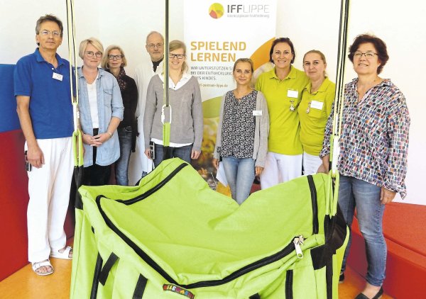 (von links) Dr. Günther Golla, Ergotherapeutin Antonia Gerstenberg, Motopädin Christiane Richter-Teles, Professor Thomas Brune, die Kinder- und Jugendpsychologinnen Tabea Brakhage und Agnieszka Wieler, die Physiotherapeutinnen Sandra Krause und Anna Kunze-Janzen sowie Marie-Luise Dresing, Pädagogische Leiterin des IFF. Die große grüne Schaukeltasche gehört zum Inventar des Therapieraums in der Röntgenstraße. - © Astrid Sewing