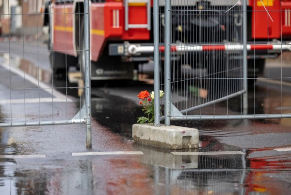 Blumen stehen nach dem Brand mit zwei toten Feuerwehrleuten in Sankt Augustin. - © Thomas Banneyer/dpa