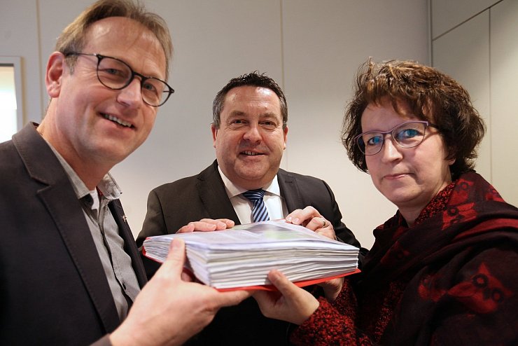 Iris Beverung und Pfarrer Dieter Bökemeier überreichen Landrat Dr. Axel Lehmann (Mitte) die Unterschriftenlisten. - © Vera Gerstendorf-Welle