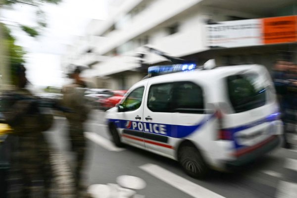 Ein Polizeiauto fährt zur Schule. - © Loic Venance/AFP/dpa