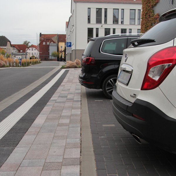 Wer am Rathaus parkt, muss den Gehweg frei lassen. Das weiße Auto steht richtig. Der schwarze Kombi riskiert ein Knöllchen, da er auf den schmalen Gehweg ragt. - © Dieter Asbrock