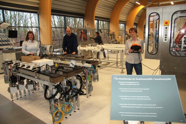 In der intelligenten Fabrik der Zukunft: (von links) Melissa Paris, Benedikt Lücke, Sascha Heymann (im Hintergrund) und Andrea Huxol bereiten die einzelnen Module für die Inbetriebnahme vor. - © Thomas Reineke