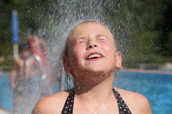 Im Schatten sind es gut 30 Grad, in der Sonne noch viel mehr. Die neunjährige Kim genießt die kalte Dusche im Freibad Heiden. - © Bernhard Preuß