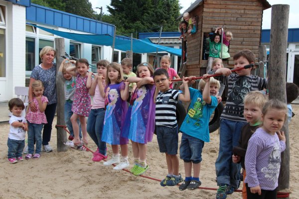 Leiterin Claudia Haustein (links im Bild) stellt sich mit einigen Kindern der Kita „Schatztruhe" auf dem Spielplatz zum Jubiläumsfoto auf.  - © Marlen Grote