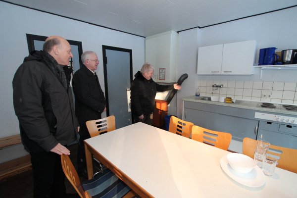 Im Küchenbereich: Linthildis Ziemer vom Deutschen Erholungswerk zeigt Kämmerer Rolf Stodiek und Bürgemeister Klaus Geise (von rechts) eins von 30 Ferienhäusern des Feriendorfes, wo Flüchtlinge untergebracht werden. - © Patrick Bockwinkel