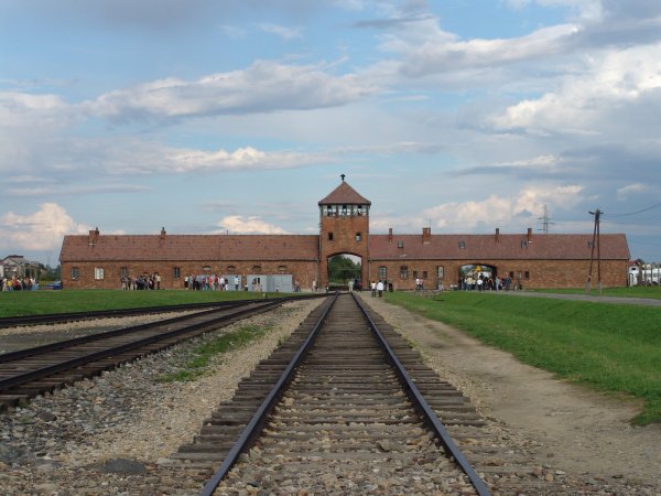 Symbol für den Ort des Grauens: Das Haupttor des KZ Auschwitz II (Birkenau). Der Blick fällt aus dem Lager heraus in Richtung Rampe, wo die deportierten Juden ankamen und selektiert wurden. - © Wikipedia