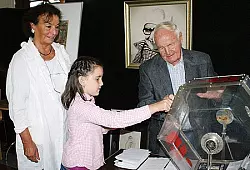 Die achtj&auml;hrige Jele greift zur Lostrommel. Wilhelm B&uuml;ker und Karin Schmidt schauen zu. - &copy; Foto: Schneider