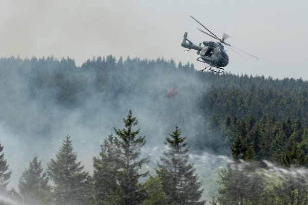 Die Feuerwehr versucht mit einem Hubschrauber einen Moorbrand im deutsch-belgischen Grenzgebiet bei Aachen zu löschen. - © Ralf Roeger/dmp-press/dpa