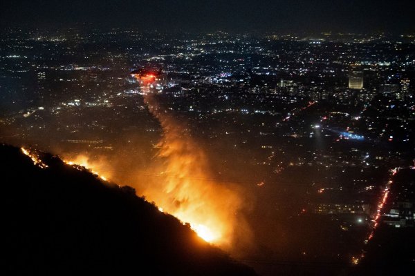 Ein Hubschrauber wirft Wasser auf das brennende Sunset Fire in den Hollywood Hills. - © Ethan Swope/AP/dpa