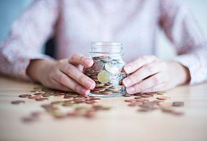 Eine Frau hält ein mit Münzen gefülltes Glas - Arne Immanuel Bänsch/dpa/dpa-tmn