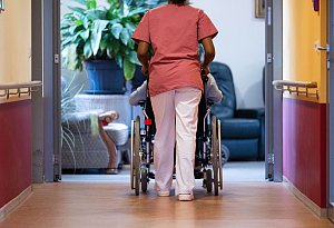 Eine Pflegekraft schiebt einen Pflegebedürftigen im Rollstuhl - Marijan Murat/dpa/dpa-tmn Eine Pflegekraft schiebt einen Pflegebedürftigen im Rollstuhl - Marijan Murat/dpa/dpa-tmn