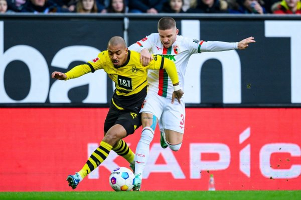 Dortmunds Donyell Malen (l) versucht den Ball vor Augsburgs Mads Pedersen (r) zu behaupten. - © Tom Weller/dpa