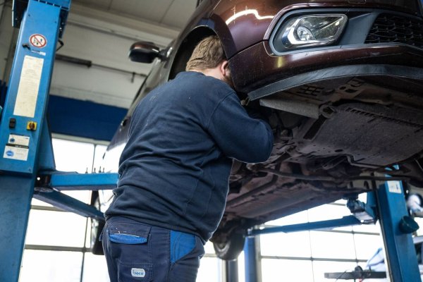 Ein Mechaniker schaut in einer Kfz-Werkstatt in den Radkasten eines Autos. - © Hannes P. Albert/dpa