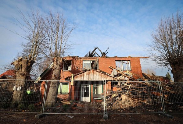 Ein Zaun der Landespolizei Schleswig-Holstein sichert das abgebrannte Haus, in dem zwei junge Menschen ums leben kamen. - © Christian Charisius/dpa