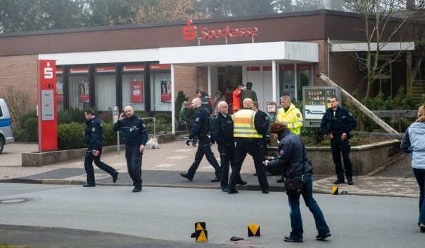 Während sich am Eingang Rettungsassistenten um die verletzten und geschockten Opfer kümmern, nehmen die Polizeibeamten die Spuren auf der Straße auf. Eine der Pistolen liegt hinten am Bordstein. - © Christian Mathiesen