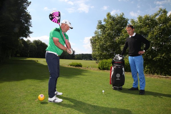 Gut in Schwung: Spielführer und Vorstandsmitglied Bernd Klemme nimmt mit beiden Händen fest den Driver in die Hand, während Golflehrer Oliver Pannhorst letzte Tipps gibt. Der Blick zeigt die neunte Spielbahn der jetzt prämierten Anlage am Schwaghof. Im Hintergrund ist das Klubhaus zu sehen. - © Gerstendorf-Welle
