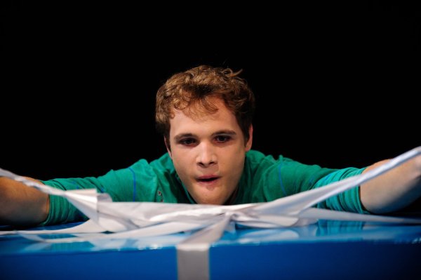 Ein Geschenk für Clemens: Lukas Schrenk in der Rolle des Clemens packt das Präsent aus, das eine ganze Menge Wirbel in sein Leben bringen soll: eine sehr lebendige Puppe namens Blaster. - © Landestheater/Klein