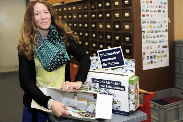 Gut gefüllte Box: Laureen Gäde sortiert in der Briefmarkenstelle Postwertzeichen. - © Bodelschwingshche Anstalten/Paul Schulz