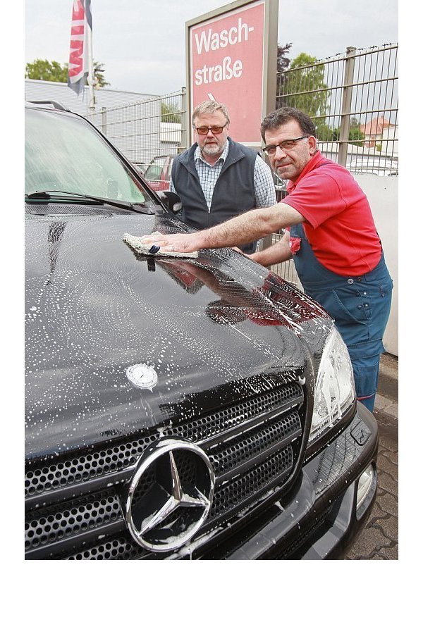 Erst einweichen, dann abwaschen: Mahmut Toker reinigt die Motorhaube vomHonigtau. Hinter ihm steht Kunde Axel Kelch aus Hiddenhausen. - © Frank-Michael Kiel-Steinkamp