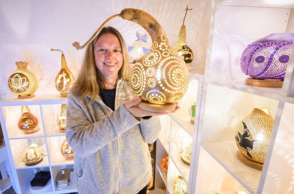 Virginia Lauterbach präsentiert eine ihrer handgefertigten Kürbislampen in der Kalebassenmanufaktur in Bückeburg. - © Julian Stratenschulte/dpa