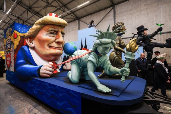 Einer der Wagen im Kölner Rosenmontagszug zeigt US-Präsident Donald Trump, der die Freiheitsstatue und die Justitia am Laufband führt. - © Oliver Berg/dpa