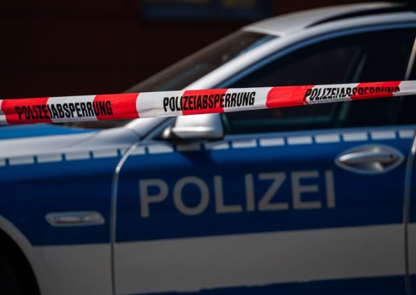 Ein Polizeiauto steht hinter einem Absperrband der Polizei. - © Robert Michael/dpa-Zentralbild/dpa/Symbolbild
