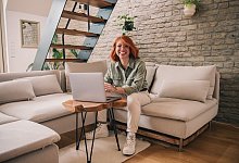 Eine Frau am Laptop sitzt auf einem Sofa - Zacharie Scheurer/dpa-tmn