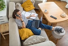 Eine Frau mit gebrochenen Fuß telefoniert auf dem Sofa - Christin Klose/dpa-tmn