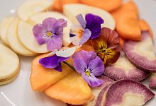 Hornveilchen liegen auf Gemüsescheiben - Zacharie Scheurer/dpa-tmn