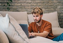 Ein Mann am Laptop auf einer Couch - Zacharie Scheurer/dpa-tmn