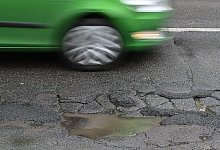 Ein Pkw f&auml;hrt auf einer Stra&szlig;e voller Schlagl&ouml;cher - Patrick Pleul/dpa/dpa-tmn