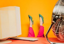 Gesch&auml;ftsfrau kopf&uuml;ber am Schreibtisch mit Ventilator - Vira Simon/Westend61/dpa-tmn