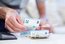 Ein Mensch z&auml;hlt Geldscheine - Christin Klose/dpa-tmn