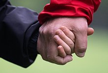 Vater und Sohn halten sich an den H&auml;nden - Hendrik Schmidt/dpa/dpa-tmn