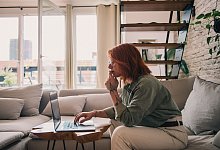 Eine Frau sitzt an einem Laptop auf einer Couch - Zacharie Scheurer/dpa-tmn
