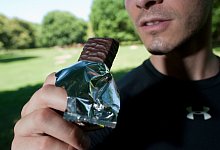 Mann isst nach dem Lauftraining einen Proteinriegel - Klaus-Dietmar Gabbert/dpa-tmn