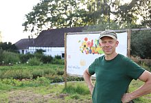 Henning Möller steht vor dem großen Schild, was den Autofahrern signalisieren soll, wo der Hof ist. Direkt daneben ist der Parkplatz. - Lena Kley