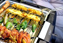 Ein Mann grillt mit einem Elektrogrill auf einem Balkon - Laura Ludwig/dpa-tmn