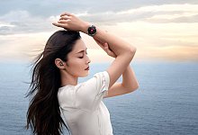Frau am Meer mit Huawei Watch Buds - Huawai/dpa-tmn