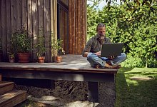 Ein Mann arbeitet am Laptop auf einer Terrasse - Maya Claussen/Westend61/dpa-tmn