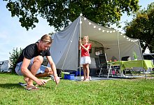 Familie baut auf Campingplatz das Vorzelt des Wohnwagens auf - Tobias Hase/dpa-tmn